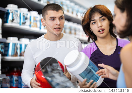 Two women and man choosing jar of sports nutrition 142518346