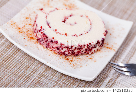 On dessert plate is slice of roll made from soft cream cheese and cranberries. On dessert plate is slice of roll made from soft cream cheese and cranberries. 142518353