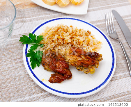 Baked chicken thighs served with rice on plate Baked chicken thighs served with rice on plate 142518400