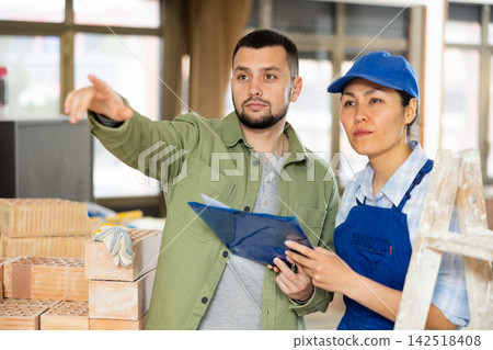 Young bearded customer discussing home renovation with female builder Young bearded customer discussing home renovation with female builder 142518408