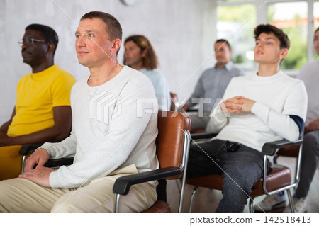Adult man listening to lecture in auditorium with male students Adult man listening to lecture in auditorium with male students 142518413