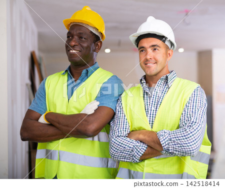 Portrait of two builders standing in apartment during repair works Portrait of two builders standing in apartment during repair works 142518414