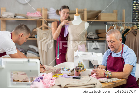Tailors work in the workshop, sew clothes and paint Tailors work in the workshop, sew clothes and paint 142518707