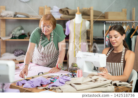 Young woman sewing, elderly woman drawing on fabric 142518736