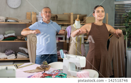 Girl and mature man sewing workshop employees do warm-up exercises Girl and mature man sewing workshop employees do warm-up exercises 142518746