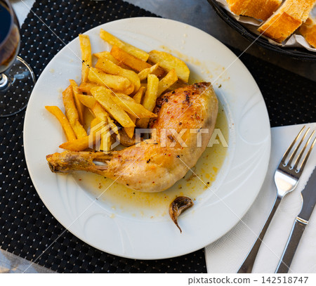 Fried chicken thigh seasoned with garlic in own juice and garnished with pieces of baked potatoes 142518747