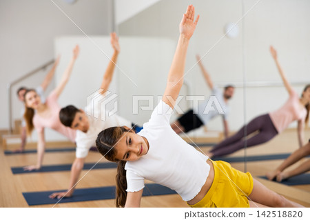 Preteen girl practicing Vasisthasana or Side Plank pose during family yoga workout Preteen girl practicing Vasisthasana or Side Plank pose during family yoga workout 142518820