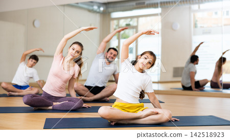 Family doing lotus pose exercises in gym Family doing lotus pose exercises in gym 142518923