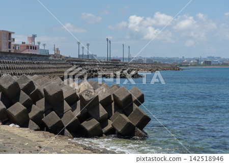 A clear blue sky and a park with streetlights visible in the distance, along a breakwater lined with wave-dissipating blocks. A clear blue sky and a park with streetlights visible in the distance, along a breakwater lined with wave-dissipating blocks. 142518946