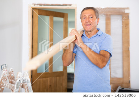 Mature man prepares place to install door in doorway 142519006