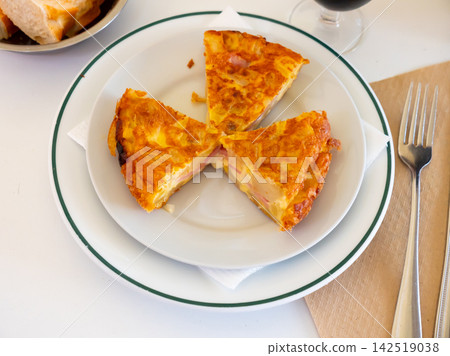 Three pieces of tortilla with potatoes and sausage served in a plate Three pieces of tortilla with potatoes and sausage served in a plate 142519038