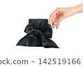 Black Friday. Hand delicately touches beautifully wrapped gift box with black bow, PNG 142519166
