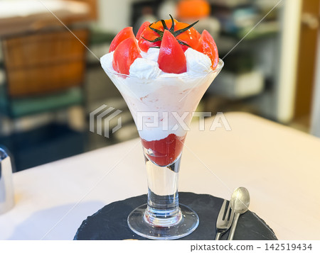A tomato parfait topped with plenty of bright red, ripe tomatoes and whipped cream. A tomato parfait topped with plenty of bright red, ripe tomatoes and whipped cream. 142519434