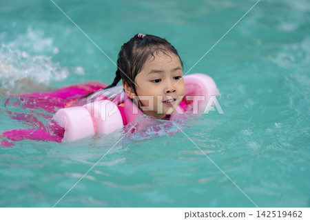preschool child girl playing and swimming with floaties in pool water preschool child girl playing and swimming with floaties in pool water 142519462
