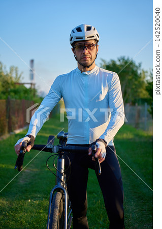 Male cyclist standing with gravel bike outdoors Male cyclist standing with gravel bike outdoors 142520040