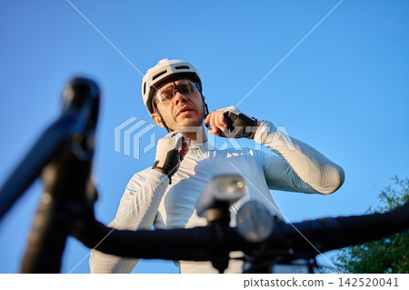 Male cyclist putting on bicycle helmet before bike ride Male cyclist putting on bicycle helmet before bike ride 142520041
