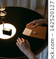 Hands Interacting on a Table with a Note and Objects 142520127