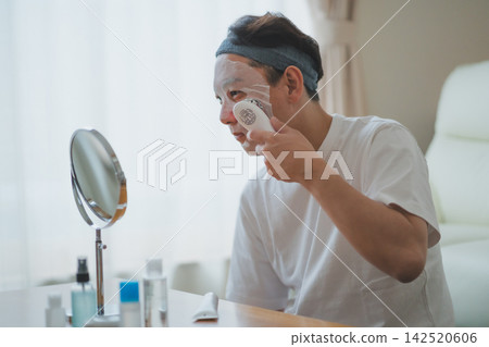 Men's beauty routine for men in their 40s: using a facial mask while receiving professional care with a facial device. Men's beauty routine for men in their 40s: using a facial mask while receiving professional care with a facial device. 142520606