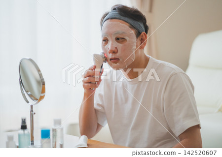A 40-something man's men's beauty routine involves using a face mask and an LED facial device for a full-fledged skincare experience. A 40-something man's men's beauty routine involves using a face mask and an LED facial device for a full-fledged skincare experience. 142520607