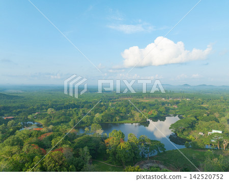 Aerial view of tropical forest surrounding freshwater lake and rubber plantation under blue sky. Sustainability, natural carbon capture, water conservation and climate resilience. Biodiversity. Aerial view of tropical forest surrounding freshwater lake and rubber plantation under blue sky. Sustainability, natural carbon capture, water conservation and climate resilience. Biodiversity. 142520752
