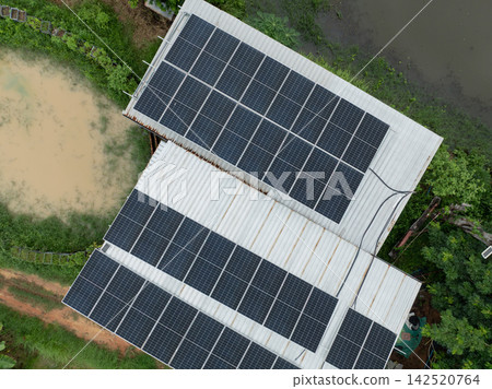 Drone view of photovoltaic solar panels installed on a metal farm roof beside water ponds during the growing season, supporting renewable power, sustainable farming and rural energy transition. Drone view of photovoltaic solar panels installed on a metal farm roof beside water ponds during the growing season, supporting renewable power, sustainable farming and rural energy transition. 142520764