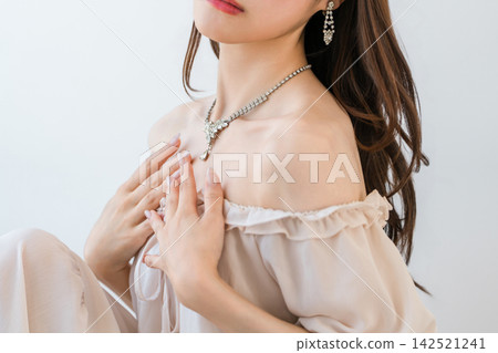 一位女士戴著一條華麗的項鍊。優雅的珠寶點綴著她的鎖骨。 一位女士戴著一條華麗的項鍊。優雅的珠寶點綴著她的鎖骨。 142521241