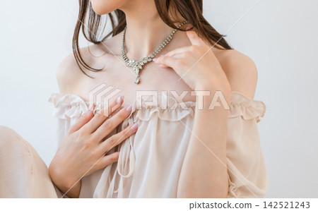 A woman wearing a glamorous necklace. Elegant jewelry adorning her décolletage. A woman wearing a glamorous necklace. Elegant jewelry adorning her décolletage. 142521243