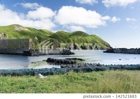 Nishikamitomari Fishing Port and clear cove on Rebun Island, Hokkaido, surrounded by blue skies and green hills. Nishikamitomari Fishing Port and clear cove on Rebun Island, Hokkaido, surrounded by blue skies and green hills. 142521683