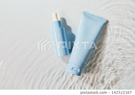 Skincare serum dropper bottle and moisturizer tube floating on water with ripples 142522167
