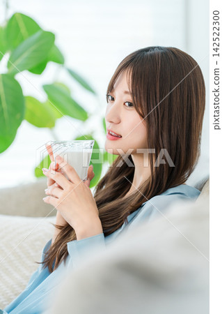 一位女士一邊喝牛奶一邊放鬆。這是一段專注於美麗和健康的舒適時光。 142522300