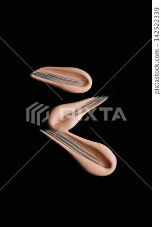 Beige liquid foundation creating smooth strokes on dark background 142522339