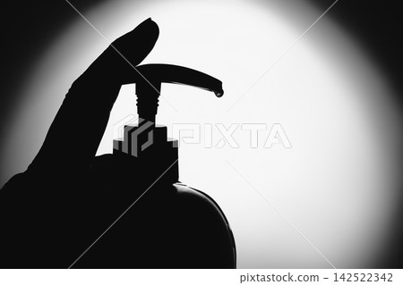 Hand pressing soap dispenser, with drop of liquid hanging from nozzle Hand pressing soap dispenser, with drop of liquid hanging from nozzle 142522342