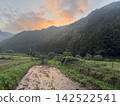 The sunrise paints the mountain ridges orange, and the tranquil countryside is a beautiful sight. 142522541