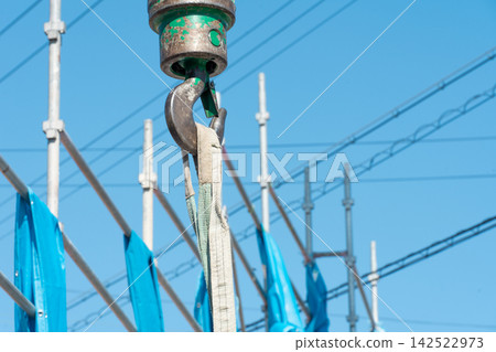 A crane hook lifts a sling at a construction site under the open sky. This is part of the rigging work for residential construction. A crane hook lifts a sling at a construction site under the open sky. This is part of the rigging work for residential construction. 142522973