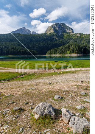 Calm lake with forest reflection under blue sky Calm lake with forest reflection under blue sky 142523342
