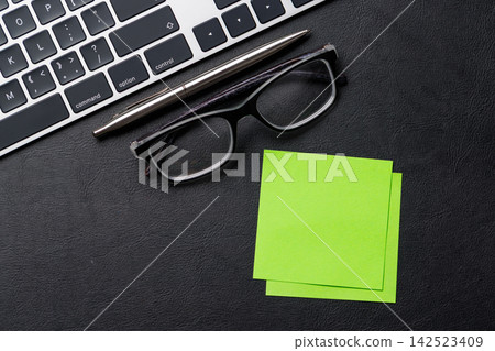 Office supplies on dark leather desk 142523409