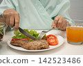 Asian elderly woman patient eating salmon stake and vegetable salad for healthy food in hospital. 142523486