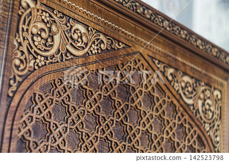 The surface of a wooden furniture element with decorative elements with religious Islamic figures and patterns. Symbolic signs, backgrounds The surface of a wooden furniture element with decorative elements with religious Islamic figures and patterns. Symbolic signs, backgrounds 142523798