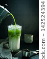 Poured Matcha green tea with Italian Moka pot pouring into a cup with iced of milk and powdered green tea on spoon on black background. copy space for your text 142524394