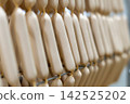 Fresh Raw Sausages Hanging on Racks in Food Processing Factory 142525202