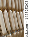Fresh Raw Sausages Hanging on Racks in Food Processing Factory 142525203