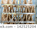 Fresh Raw Sausages Hanging on Racks in Food Processing Factory 142525204