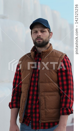 Vertical video. Portrait of a young farmer in work attire posing by hay stack. Modern organic agriculture. Vertical video. Portrait of a young farmer in work attire posing by hay stack. Modern organic agriculture. 142525256