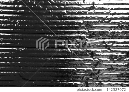 Black metallic silver foil insulation material with ridges and bubble packaging texture. Abstract dark grunge background Black metallic silver foil insulation material with ridges and bubble packaging texture. Abstract dark grunge background 142527072