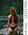 Serene woman with long wet hair in crochet top bathing in forest lake 142527890