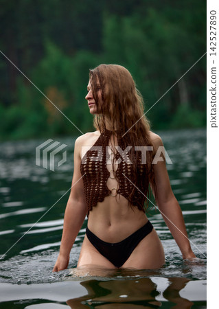 Serene woman with long wet hair in crochet top bathing in forest lake Serene woman with long wet hair in crochet top bathing in forest lake 142527890