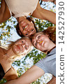 Playful young women with lollipops looking down at camera in huddle 142527930