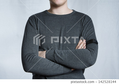 Young Man With Arms Crossed Wearing Black Armband Demonstrating Mourning And Solidarity Young Man With Arms Crossed Wearing Black Armband Demonstrating Mourning And Solidarity 142528144