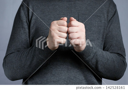 Clenched Fists Gesture Of Nervousness And Tension By Person Wearing Dark Sweater Clenched Fists Gesture Of Nervousness And Tension By Person Wearing Dark Sweater 142528161