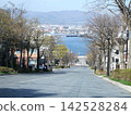 A sloping street overlooking the harbor and a view of the townscape 142528284